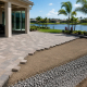 Paver patio base preparation and installation in progress at a Florida home, with compacted gravel base and palm trees in background