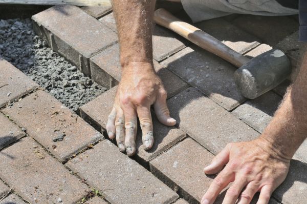 Paver repair contractor hands-on fixing damaged brick pavers in Wesley Chapel FL
