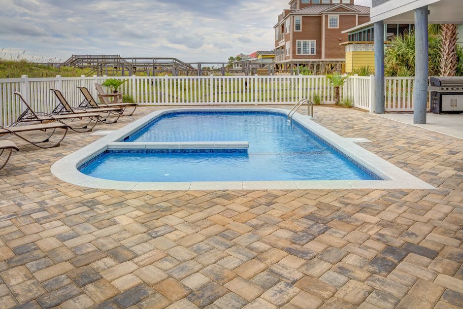 Pool deck with large brick pavers surrounding a residential swimming pool in Tampa, FL