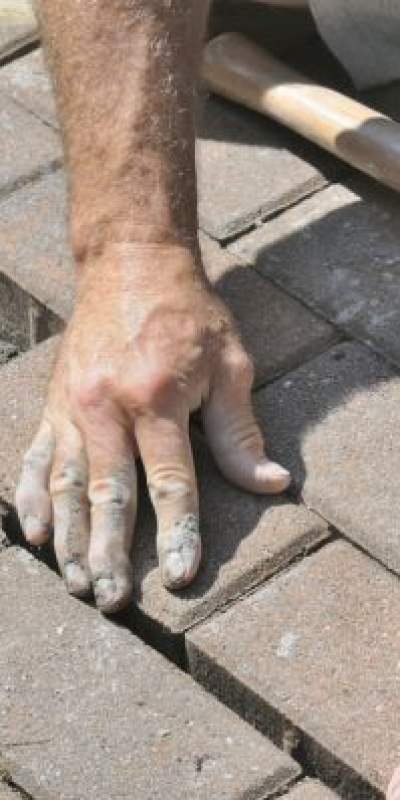 Paver repair contractor hands-on fixing damaged brick pavers in Wesley Chapel FL